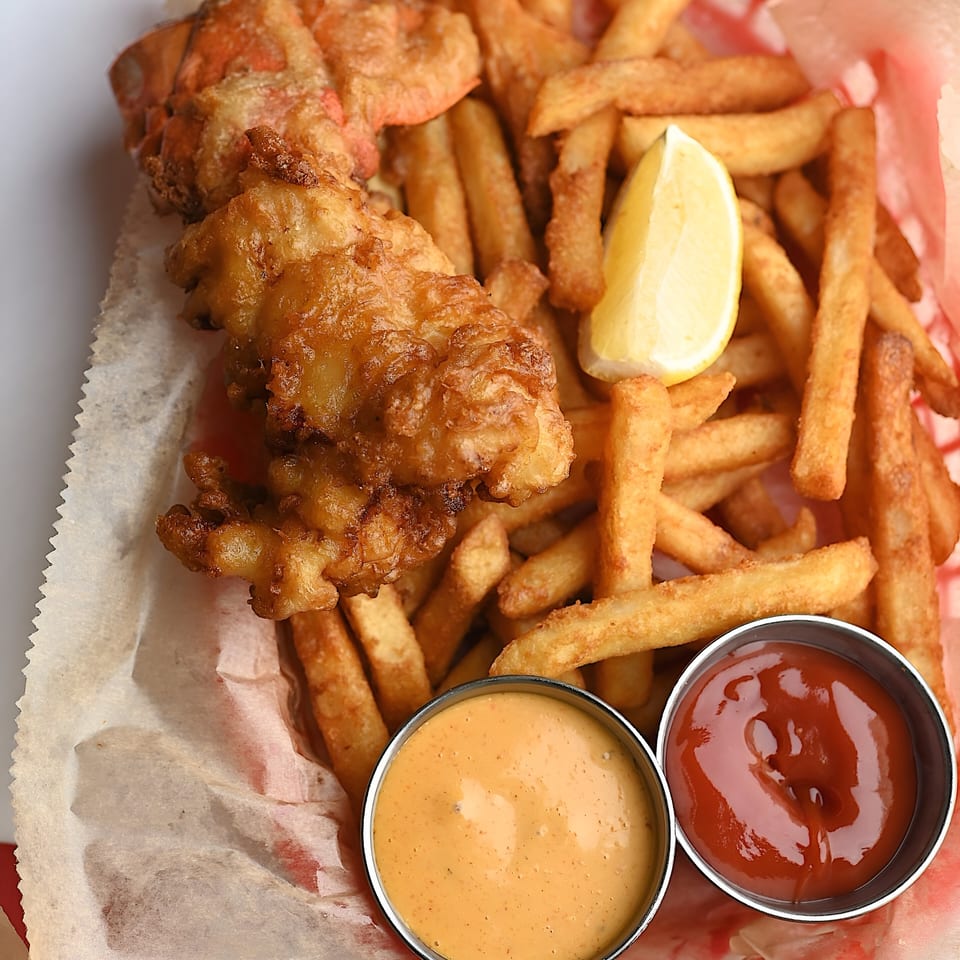 Shaking Crab's fried lobster tail and french fries with lemon, ketchup, and a creamy dipping sauce.